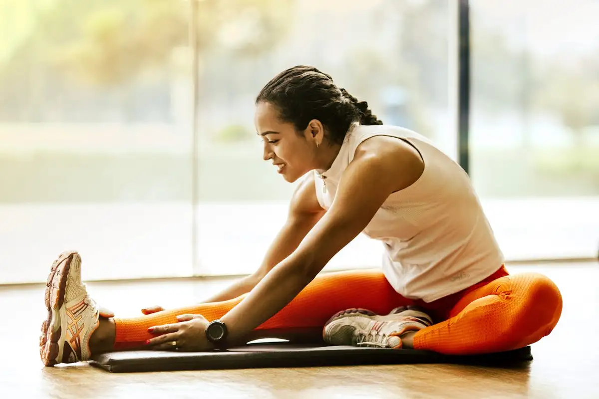 estiramientos-preparacion-fisica-mujer-gimnasio Mujer haciendo estiramientos en el gimnasio como parte de su rutina f铆sica